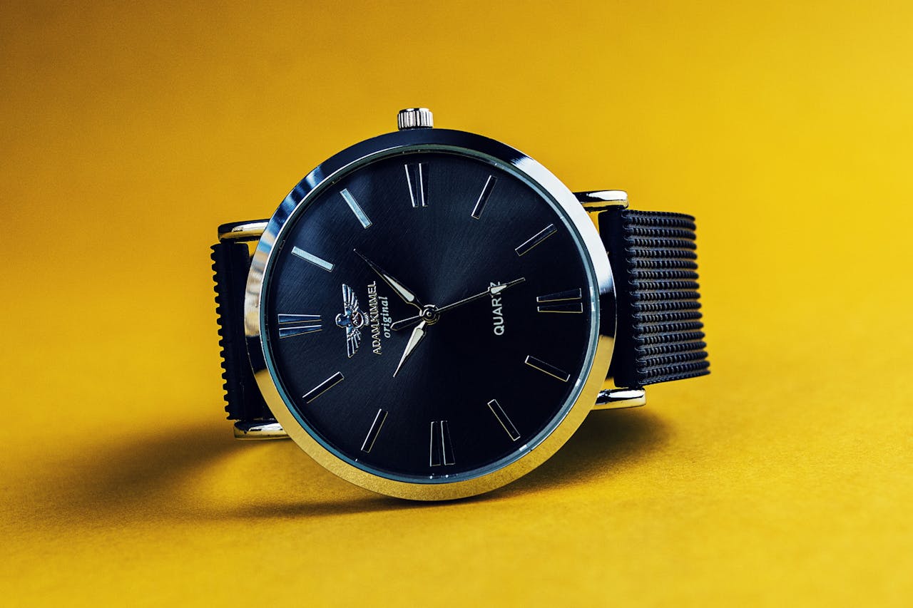 Stylish black analog wristwatch with a black strap on a vibrant yellow background.